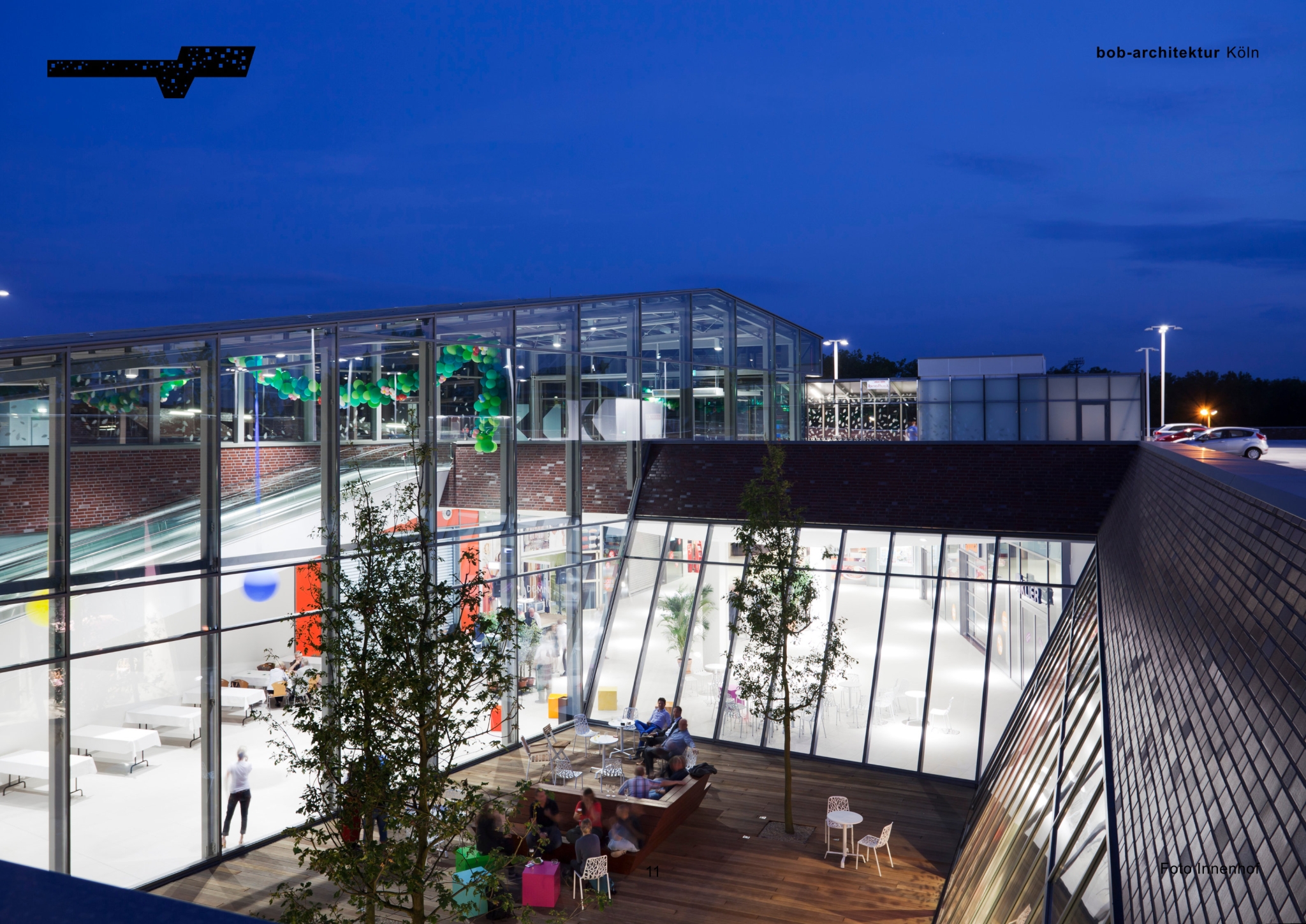 Innenhof mit Glasdach und offenen Aufenthaltsbereichen in einem modernen Gebäudekomplex bei Nacht in Kamp-Lintfort am Niederrhein